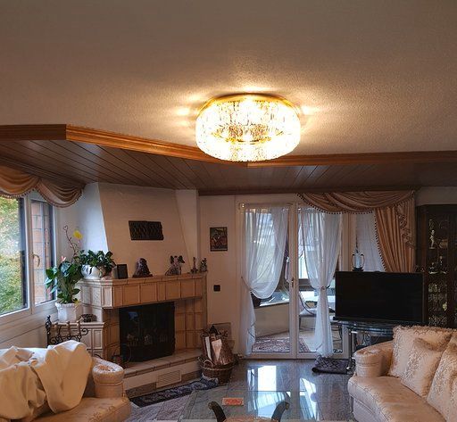 Ein Wohnzimmer mit Couch, Kamin, Fernseher und Kronleuchter.