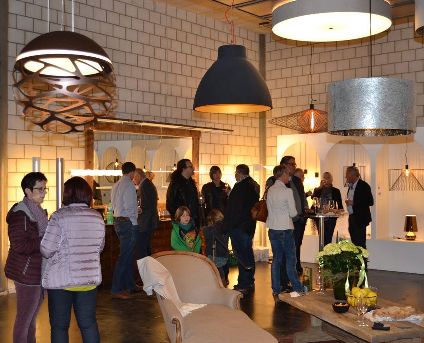 Eine Gruppe von Menschen versammelt sich in einem Raum mit vielen Lichtern, die von der Decke hängen