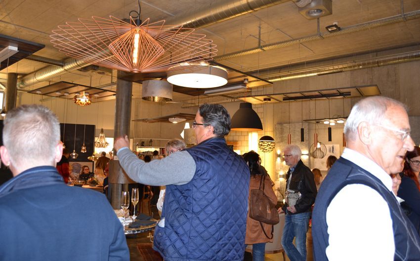 Eine Gruppe von Menschen steht in einem Raum und schaut auf eine Deckenleuchte.