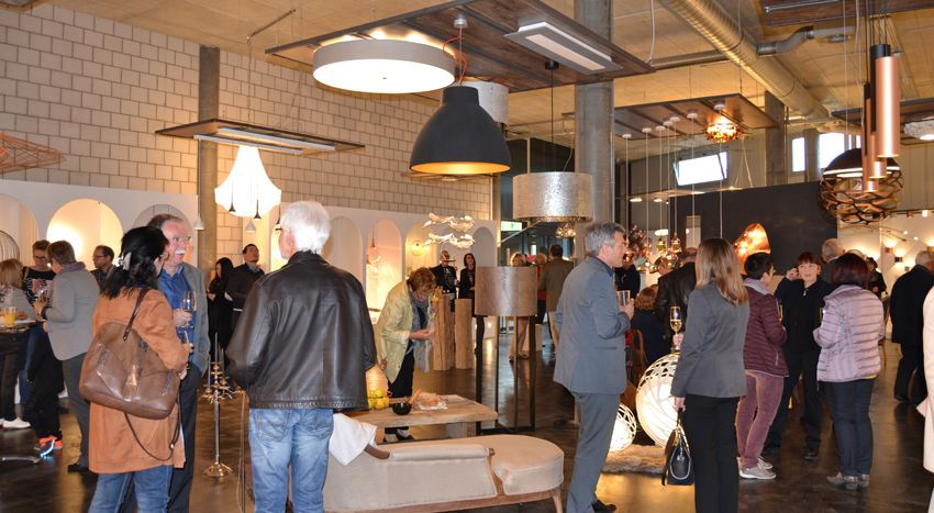 Eine Gruppe von Leuten steht in einem Raum, von dessen Decke viele Lichter hängen.