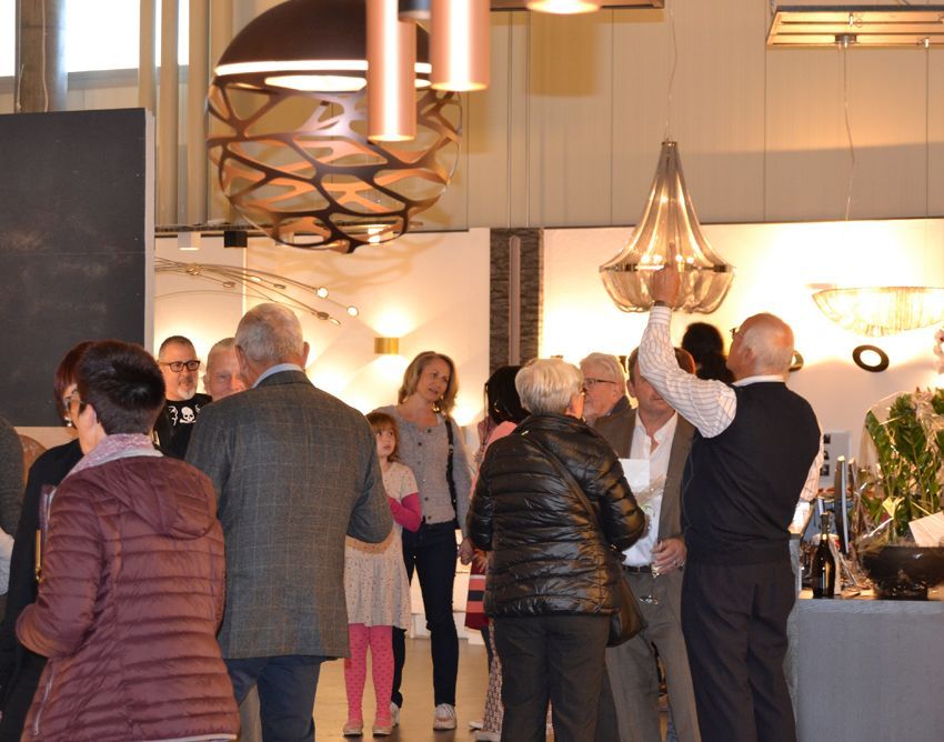 Eine Gruppe von Menschen steht in einem Raum, an dessen Decke ein Kronleuchter hängt