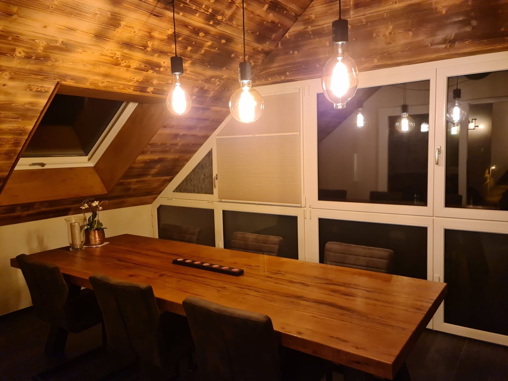 Ein Esszimmer mit einem Holztisch und Stühlen und einem Fenster.