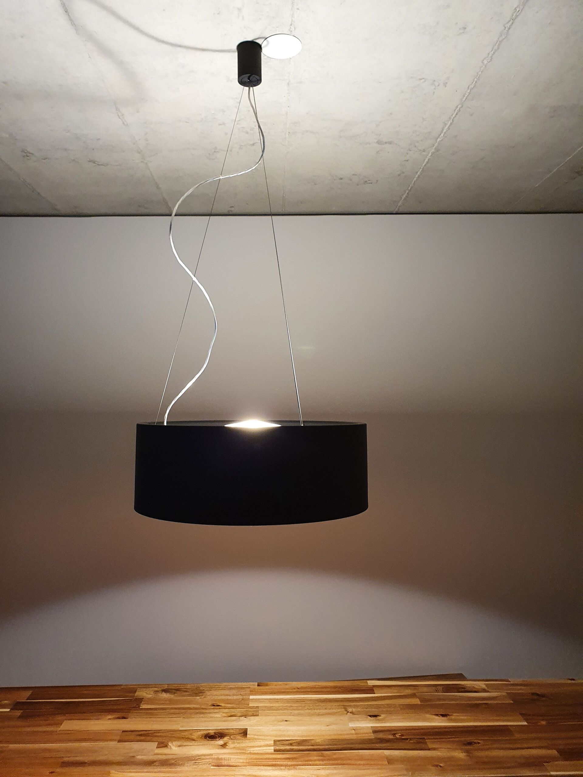 Eine schwarze Lampe hängt von der Decke in einem Raum
