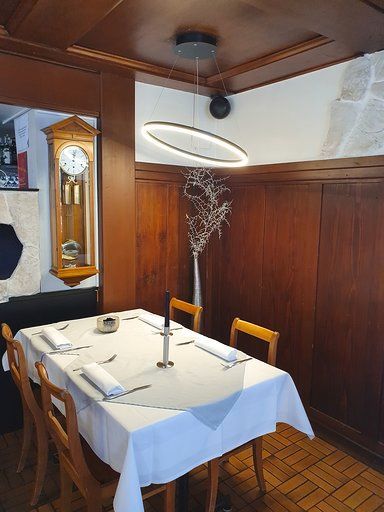 Ein Esszimmer mit einem Tisch und Stühlen und einer Uhr an der Wand.