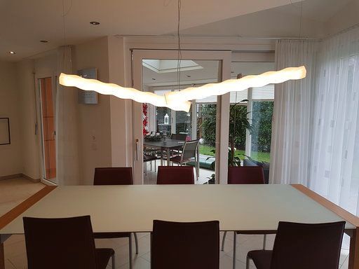 Ein Esszimmer mit einem Tisch und Stühlen und einer Lampe, die von der Decke hängt.