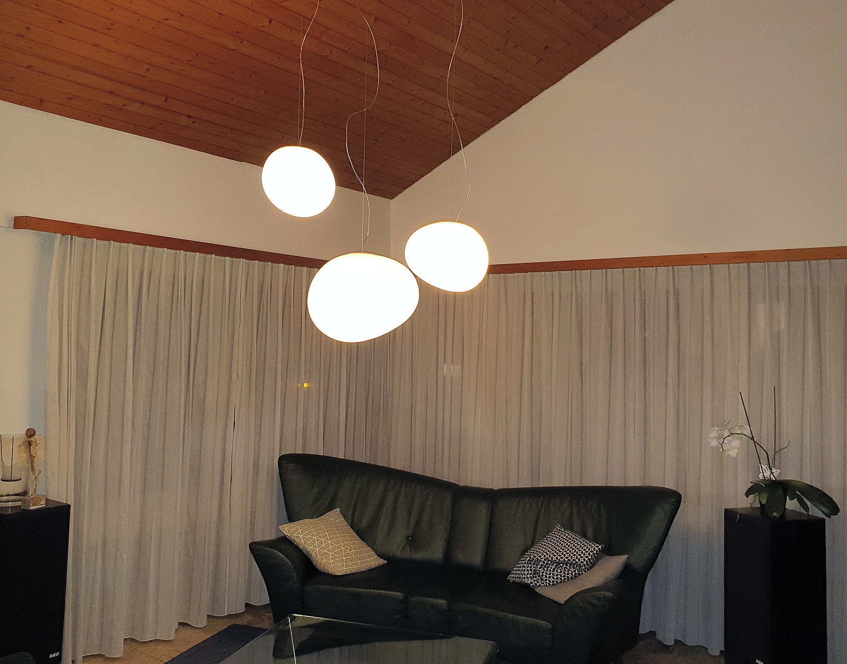 Ein Wohnzimmer mit einer schwarzen Couch und weißen Vorhängen