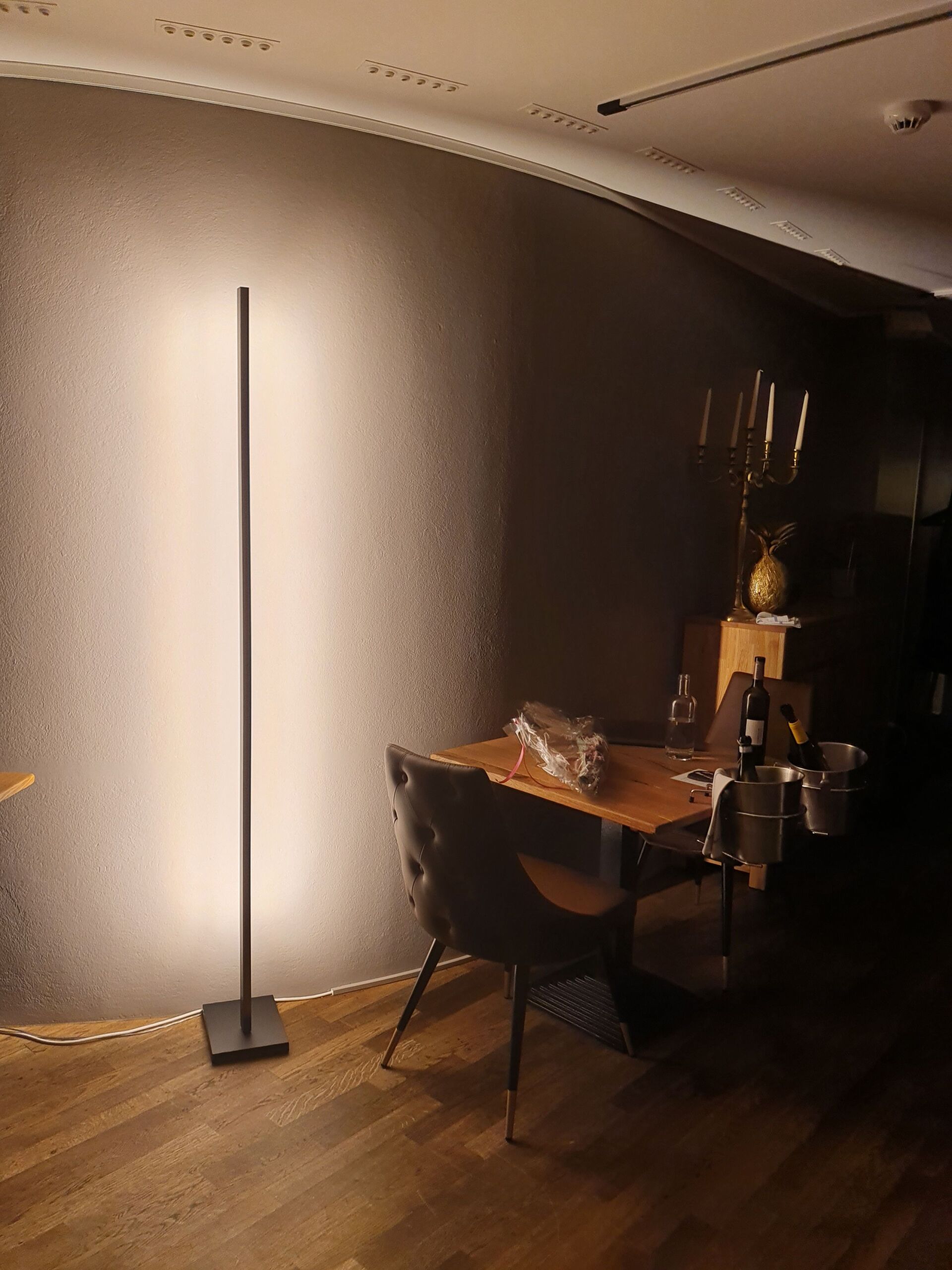 Ein Raum mit einem Tisch und Stühlen und einer Lampe auf dem Boden