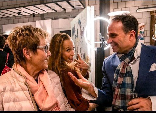 Ein Mann in Anzug und Schal spricht mit zwei Frauen und einem kleinen Mädchen.