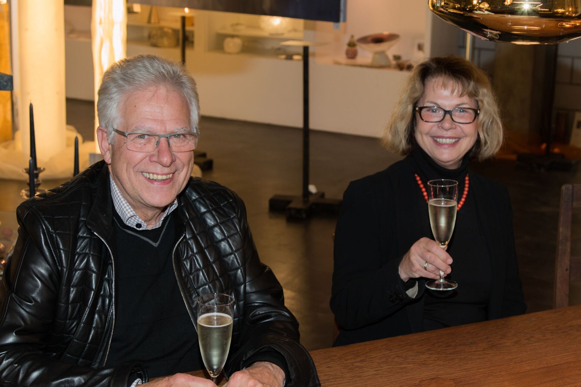 Ein Mann und eine Frau sitzen mit Champagnergläsern an einem Tisch.