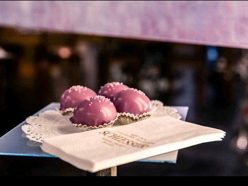 Drei lila Cupcakes liegen auf einer Serviette auf einem Glasteller.