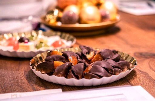 Auf einem Holztisch steht ein Teller mit schokoladenüberzogenen Früchten.