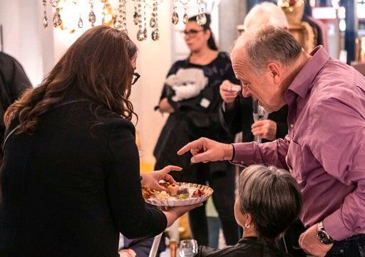 Auf einer Party gibt ein Mann einer Frau einen Teller mit Essen.