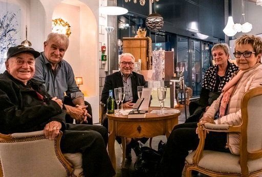 Eine Gruppe von Leuten sitzt in einem Raum um einen Tisch herum.