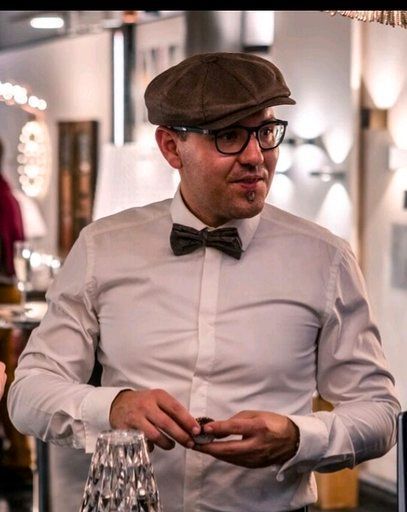 Ein Mann mit Hut und Fliege steht in einem Raum.