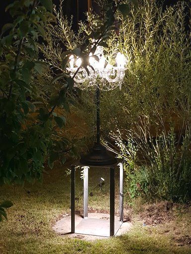 Ein Laternenpfahl mit einem daran hängenden Kronleuchter ist nachts beleuchtet.