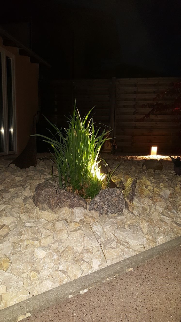 Eine kleine Anlage ist von Felsen umgeben und nachts beleuchtet.