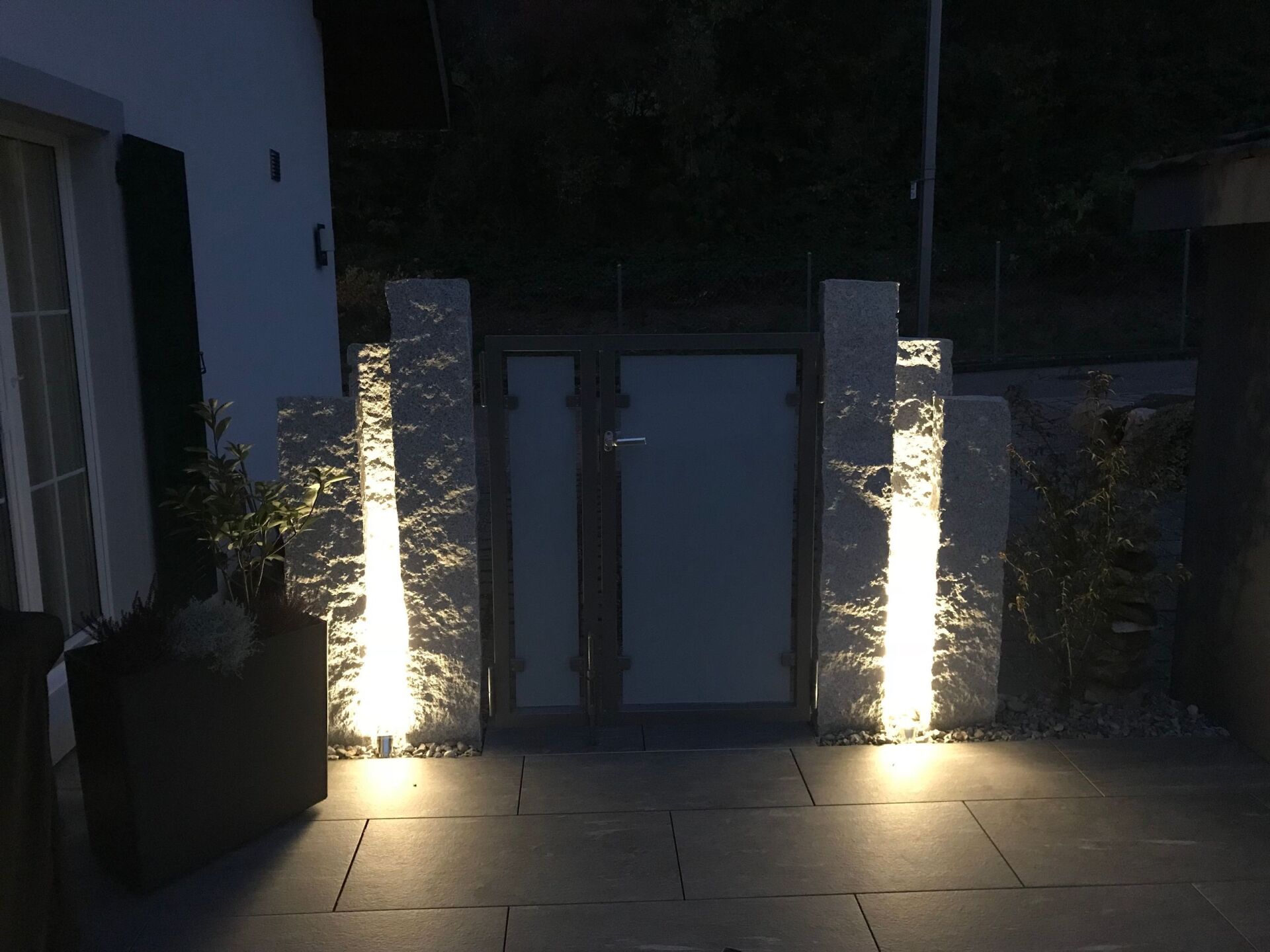 Vor einer Tür sind zwei Säulen beleuchtet