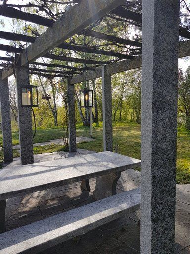 Eine Pergola mit einem Tisch und Bänken darunter in einem Park.