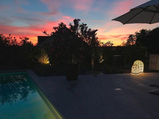 Ein Sonnenuntergang über einem Swimmingpool mit einem Sonnenschirm im Vordergrund