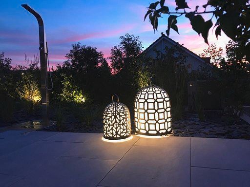 Auf einer Terrasse leuchten nachts zwei Laternen.