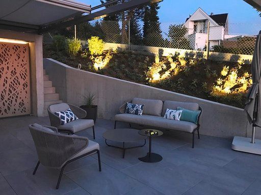 Eine Terrasse mit Sofa, Stühlen, Tisch und Sonnenschirm für die Nacht.
