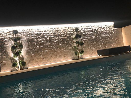 Ein Swimmingpool mit einem Wasserfall im Hintergrund bei Nacht.