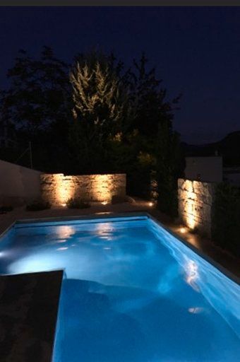 Ein großes Schwimmbecken ist nachts beleuchtet.