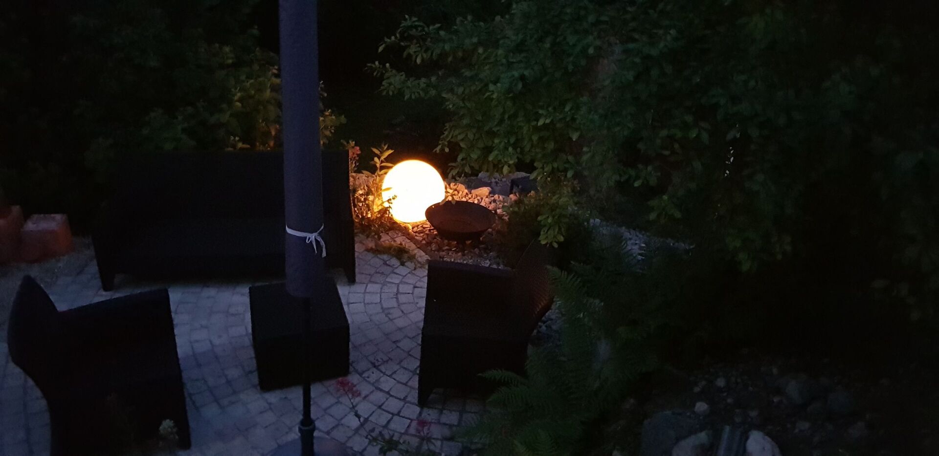 Eine Terrasse mit Feuerstelle und Licht in der Nacht.