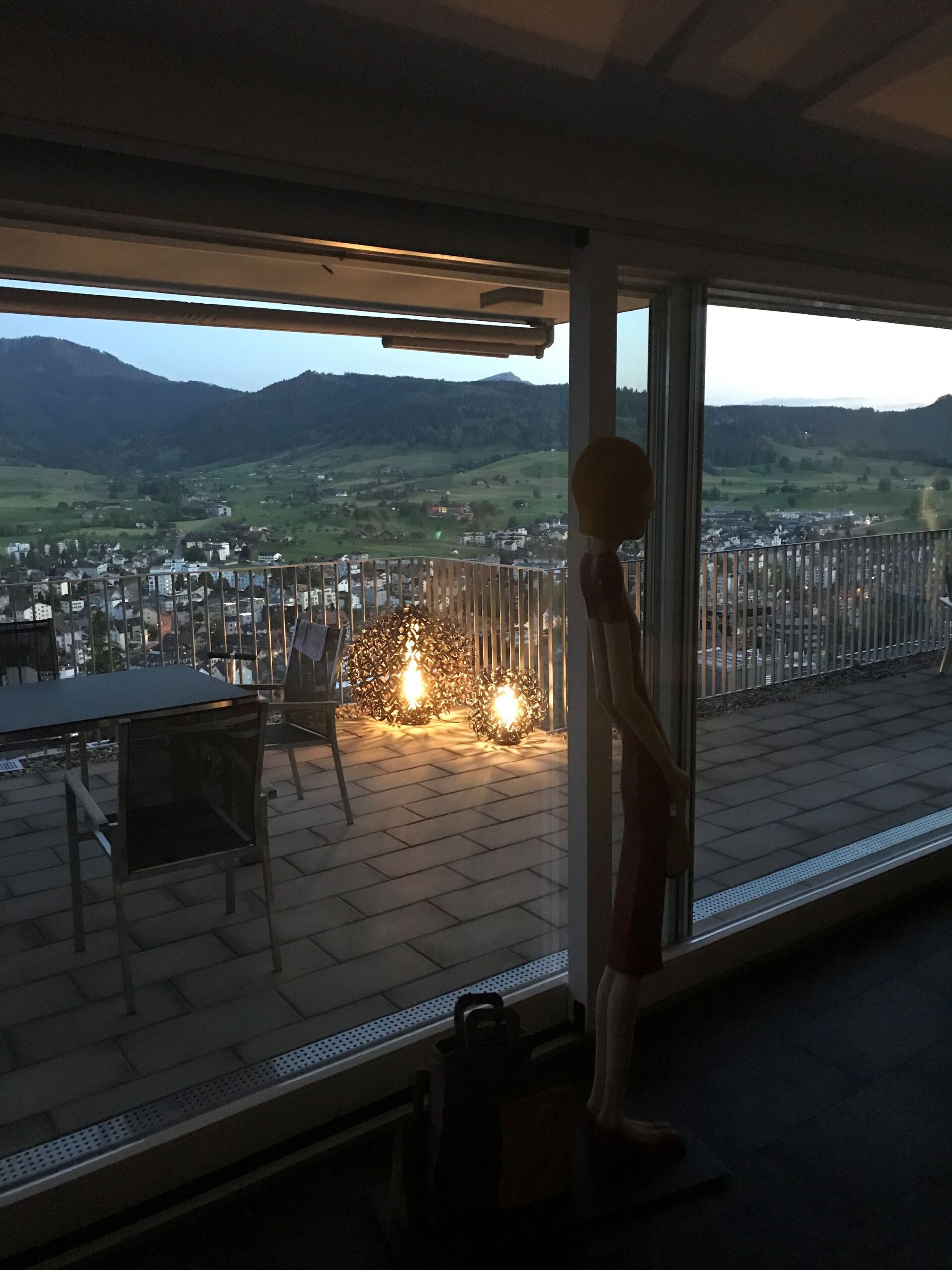 Eine Person steht vor einem Fenster mit Blick auf eine Stadt.
