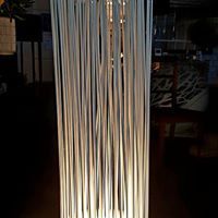 Eine große Glasvase mit einer Lampe darin steht auf einem Tisch in einem dunklen Raum.