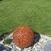 Eine rostige Kugel liegt inmitten eines üppigen grünen Rasens.