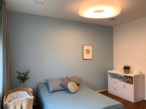 Ein Schlafzimmer mit Bett, Kommode und Bild an der Wand.