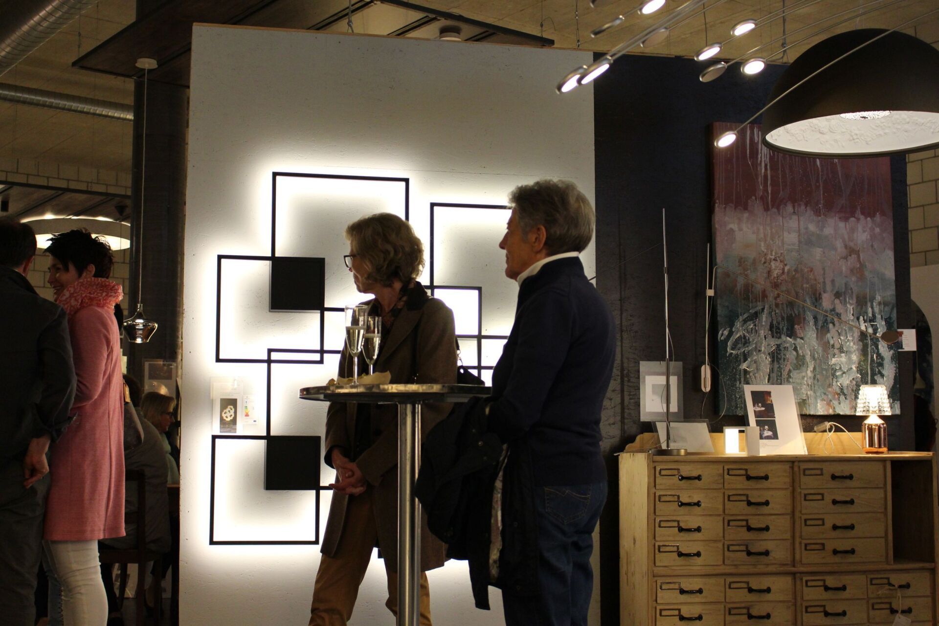 Eine Gruppe von Menschen steht vor einer Wand mit Quadraten darauf