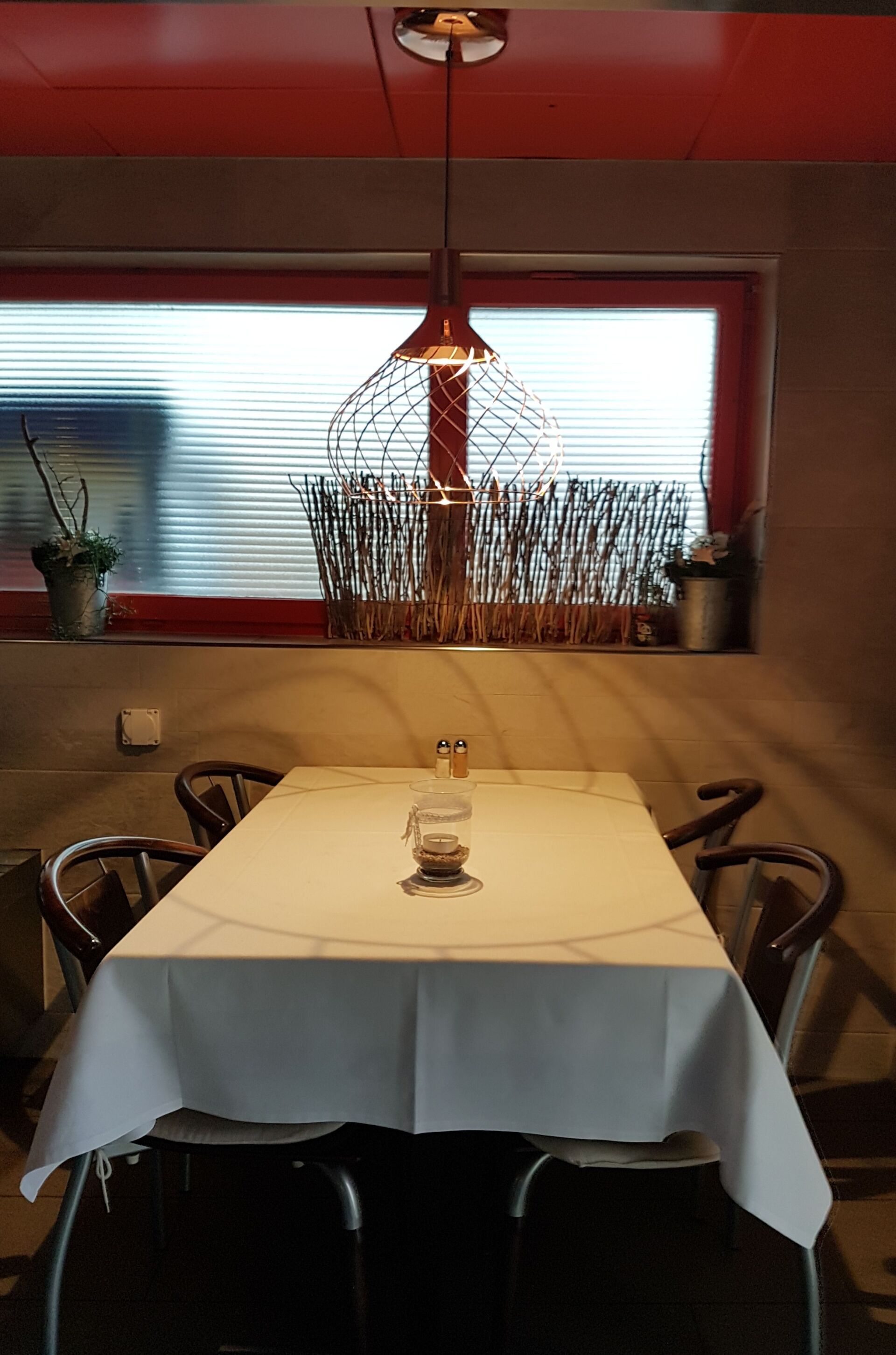 Ein Tisch mit weißer Tischdecke und Stühlen vor einem Fenster