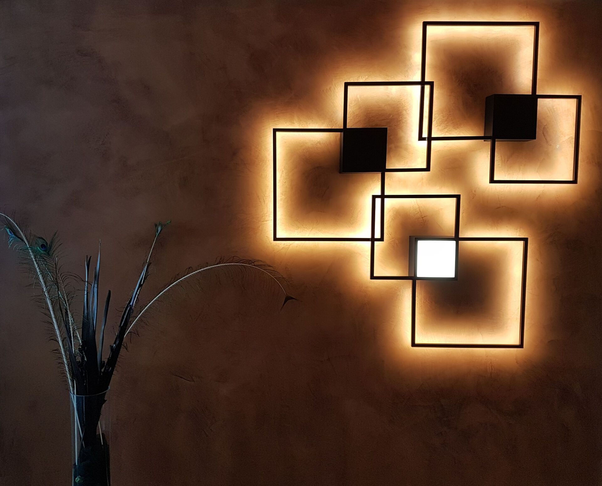 Eine Wand mit einer Lampe darauf und einer Pflanze in einer Vase