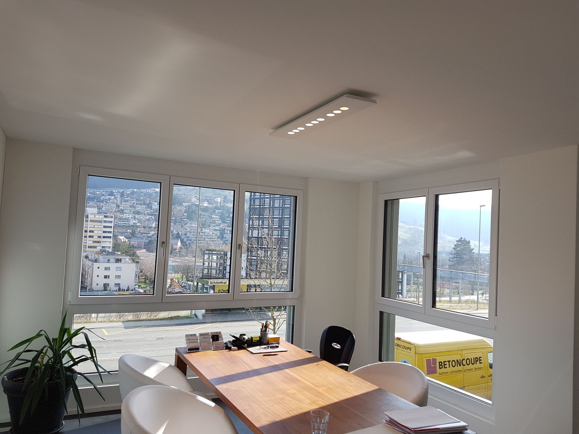 Ein Esszimmer mit Tisch und Stühlen und vielen Fenstern.