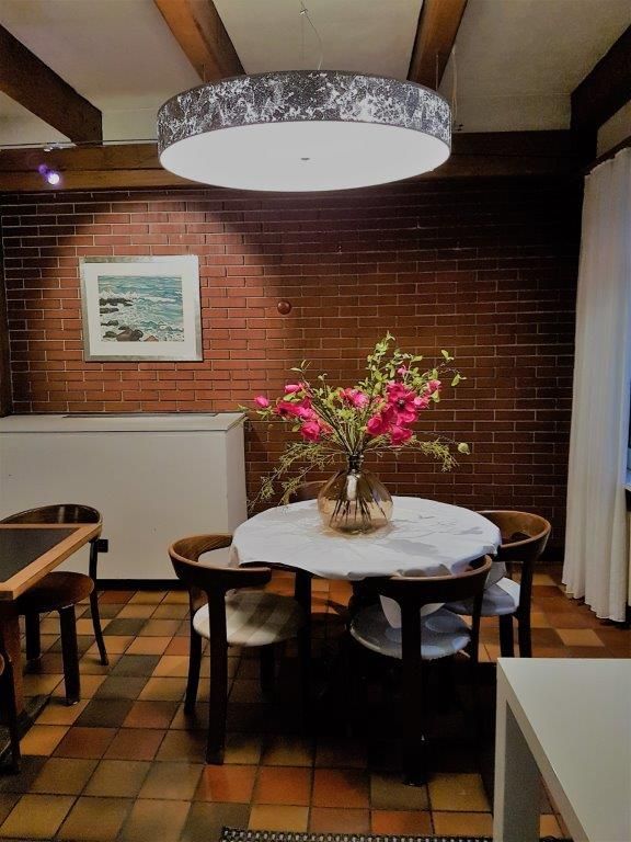 Eine Vase mit rosa Blumen steht auf einem Tisch in einem Esszimmer