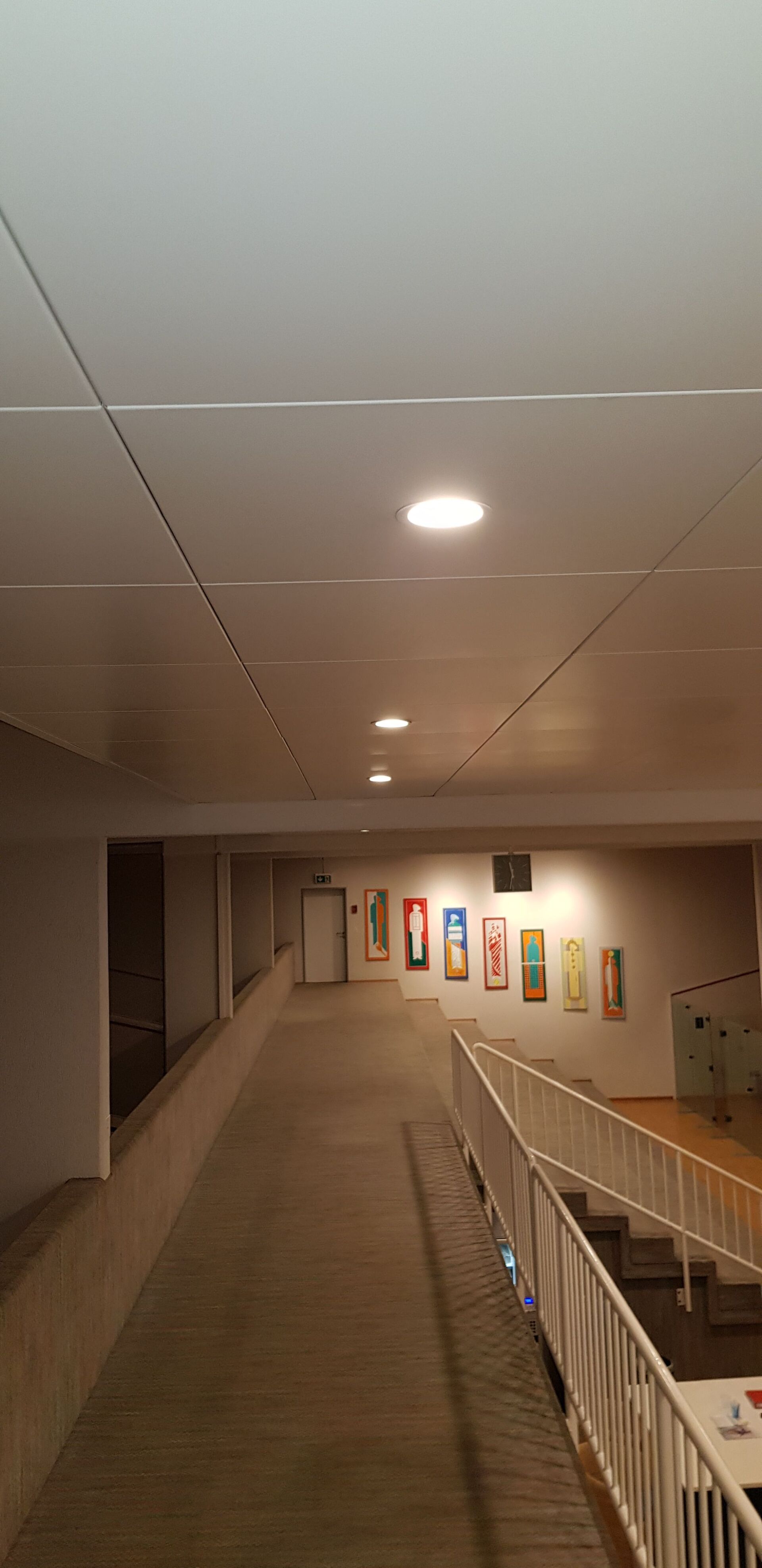 Ein langer Flur mit einer Rampe, die in den zweiten Stock eines Gebäudes führt.