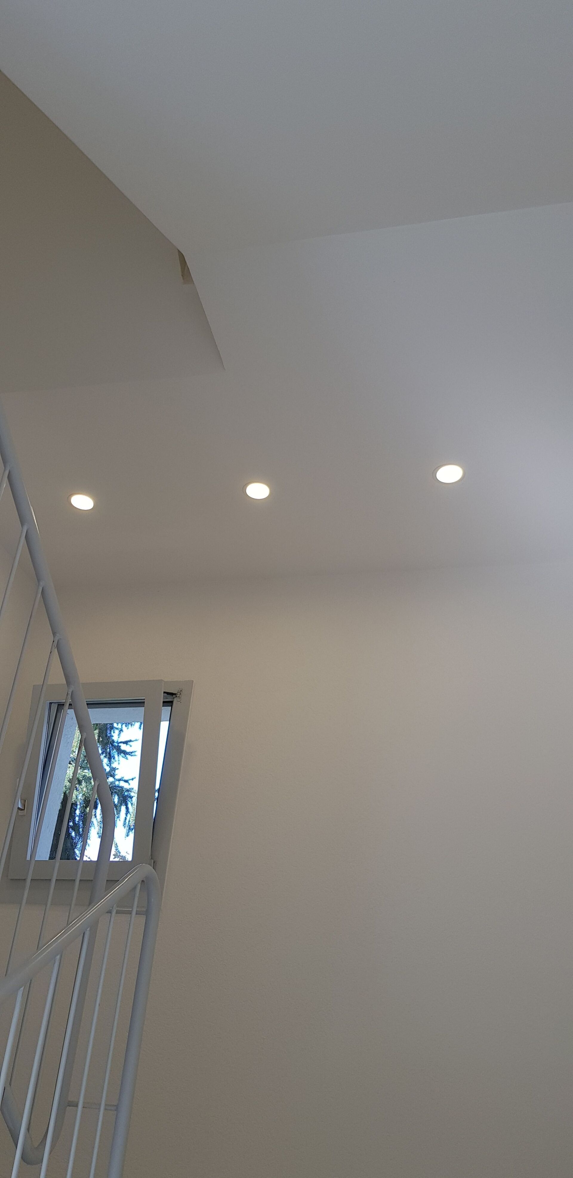 Eine Treppe mit einem Fenster und Lichtern an der Decke.