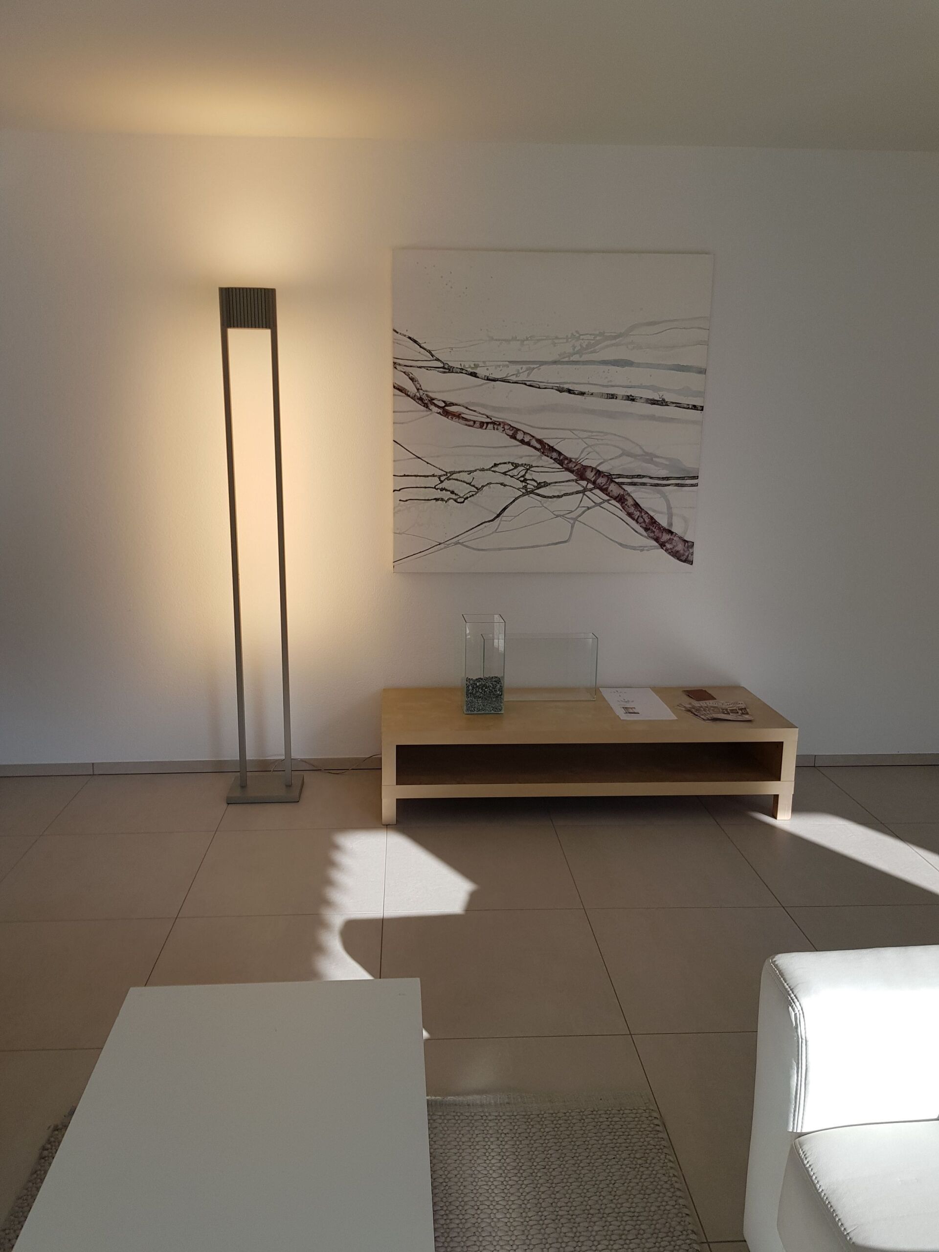 Ein Wohnzimmer mit einer Lampe und einem Gemälde an der Wand