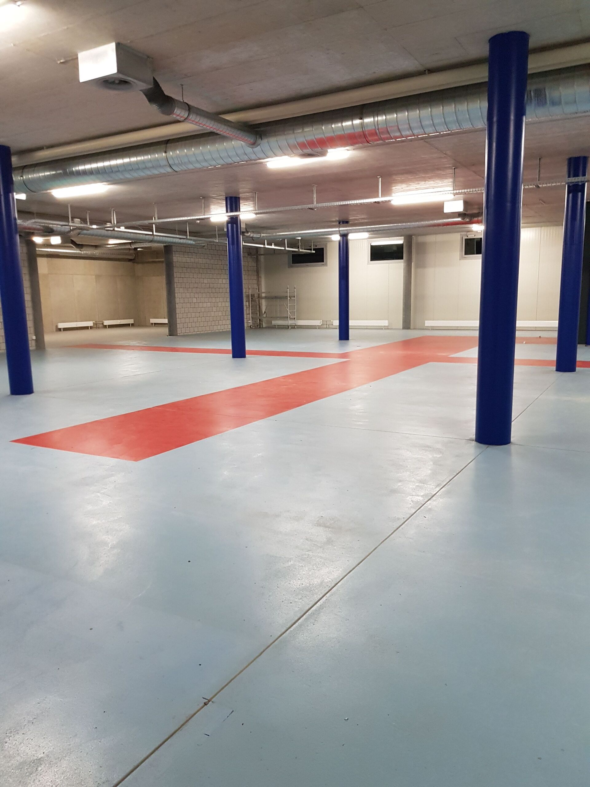 Ein großer leerer Raum mit blauen Säulen und einem roten Streifen auf dem Boden