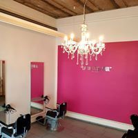 Ein Friseursalon mit einer rosa Wand und einem Kronleuchter, der von der Decke hängt.