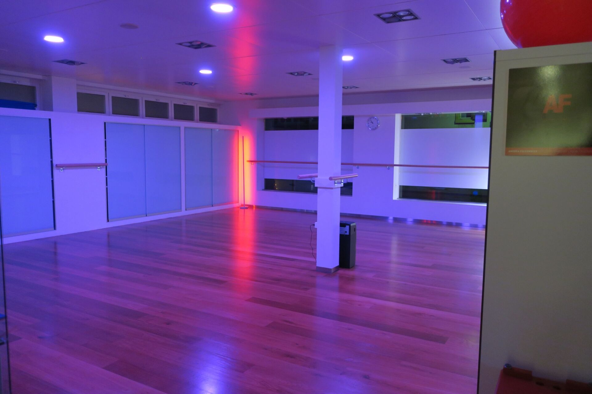 Ein großer leerer Raum mit Holzboden und violetten Lichtern