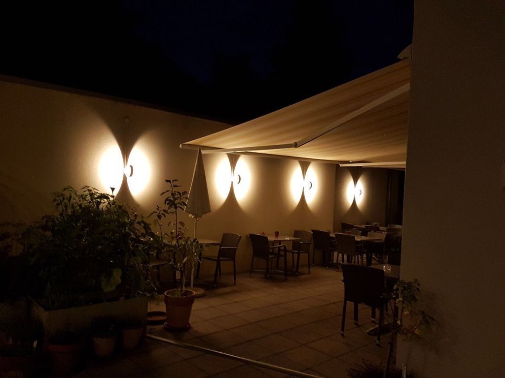 Eine Terrasse mit Tischen und Stühlen unter einer Markise bei Nacht