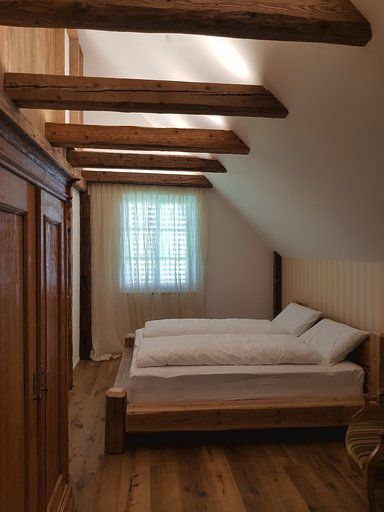 Ein Schlafzimmer mit zwei Betten, einem Fenster und Holzbalken.