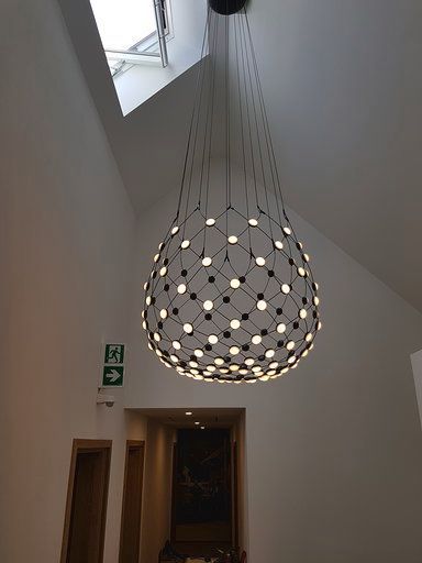 In einem Flur hängt eine große Pendelleuchte von der Decke.