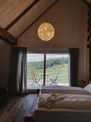 Ein Schlafzimmer mit zwei Betten und einem großen Fenster mit Jalousien.