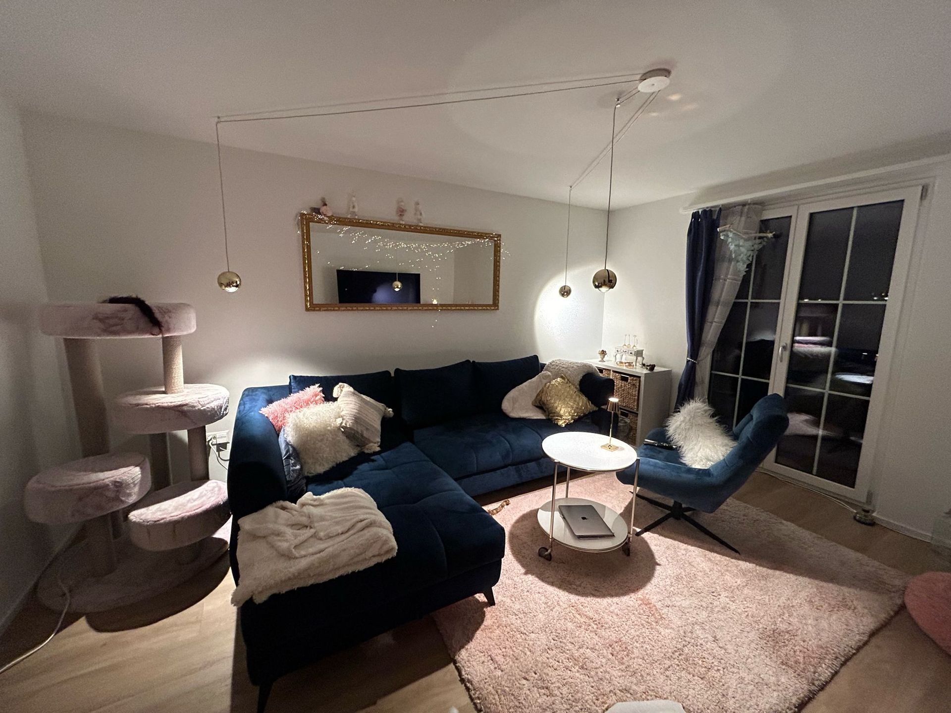 Ein Wohnzimmer mit Couch, Sessel, Tisch und Spiegel.