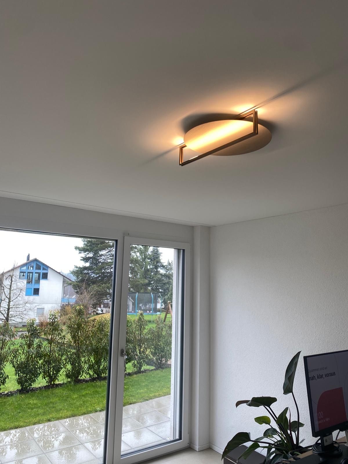 Ein Wohnzimmer mit Deckenleuchte und Glasschiebetür