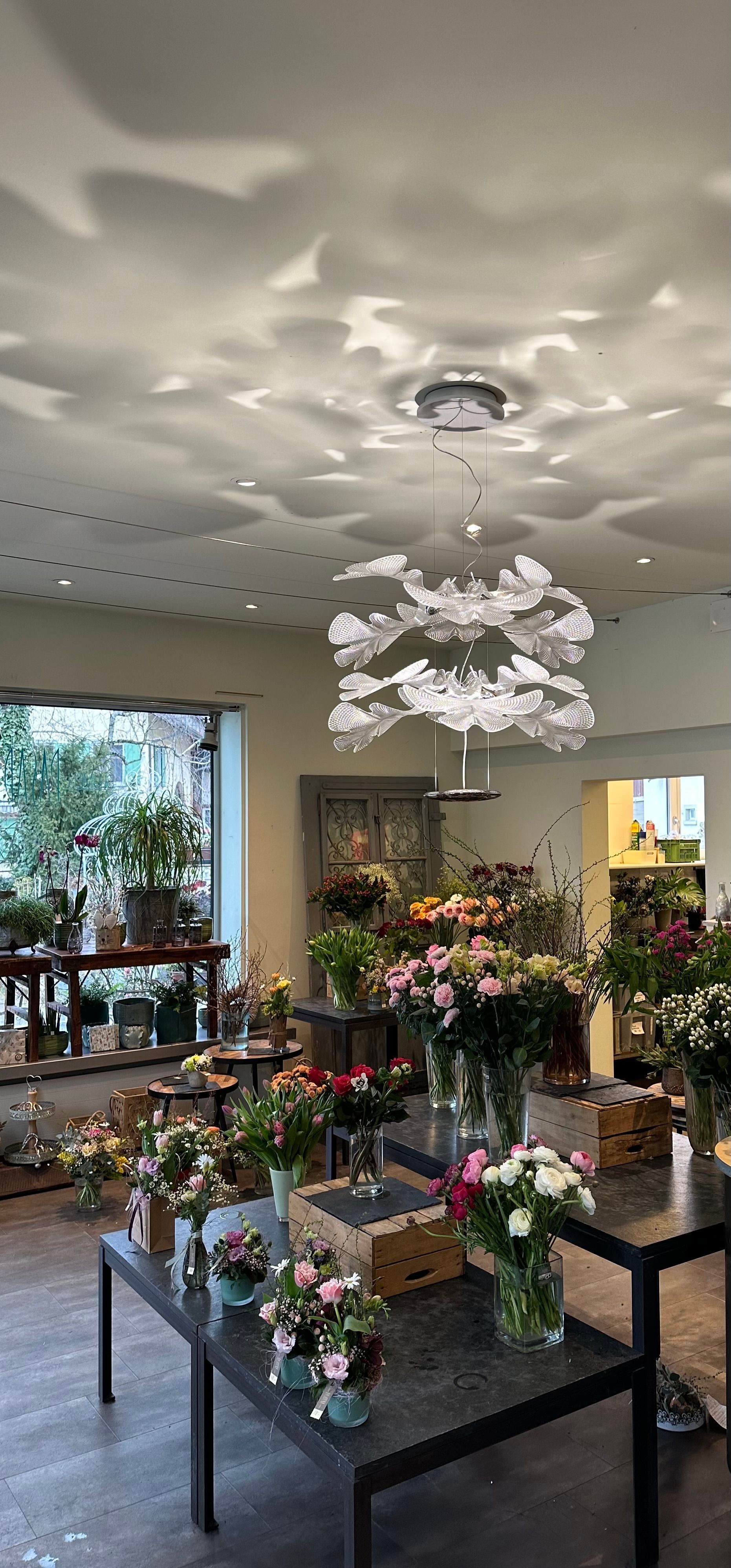 Ein Raum voller Tische, Blumenvasen und einem Kronleuchter.